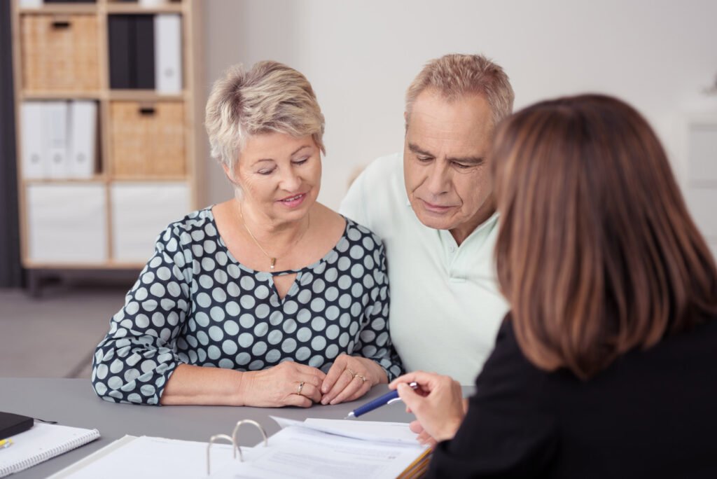 Older woman and man couple looking at contract in front of woman facing away from camera. Atwell Care Ltd. Live in care. Home Care. Care Company. Bath. Frome. Keynsham. Saltford.
